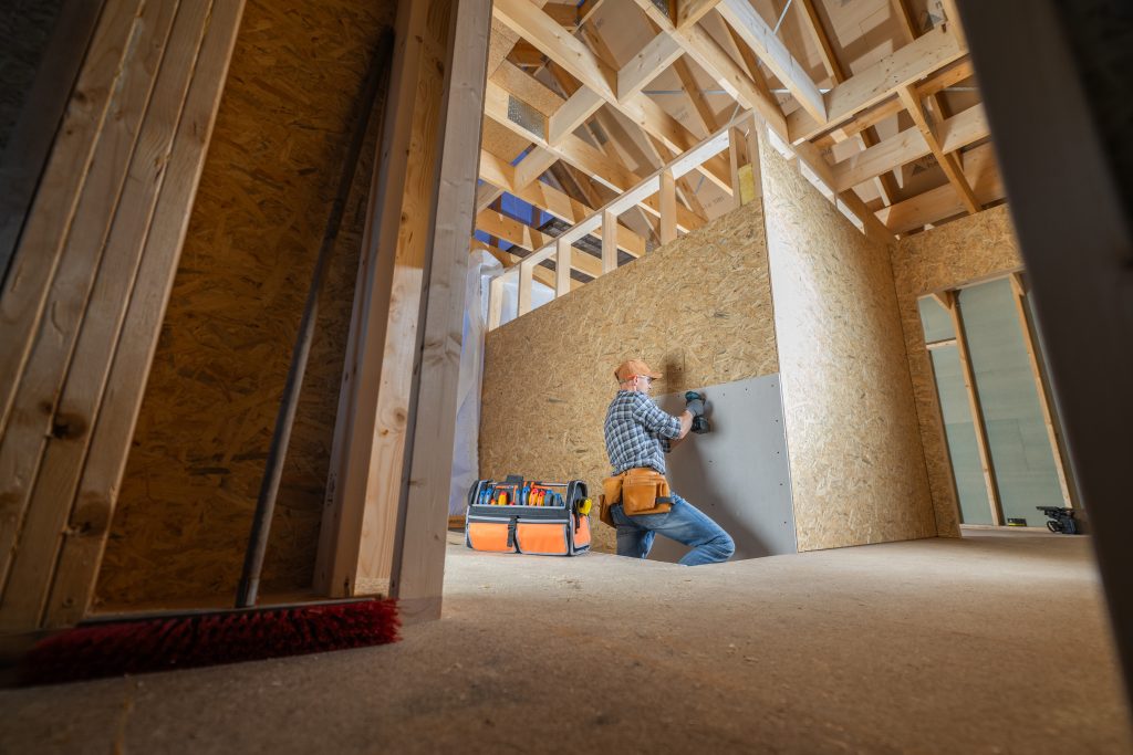 Construction worker installing drywall in a new house